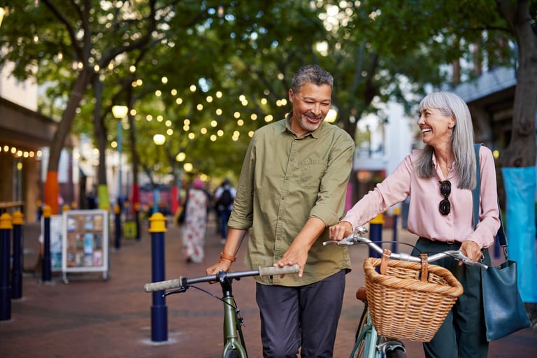 Happy retired couple walking with bicycles in town enjoying retirement