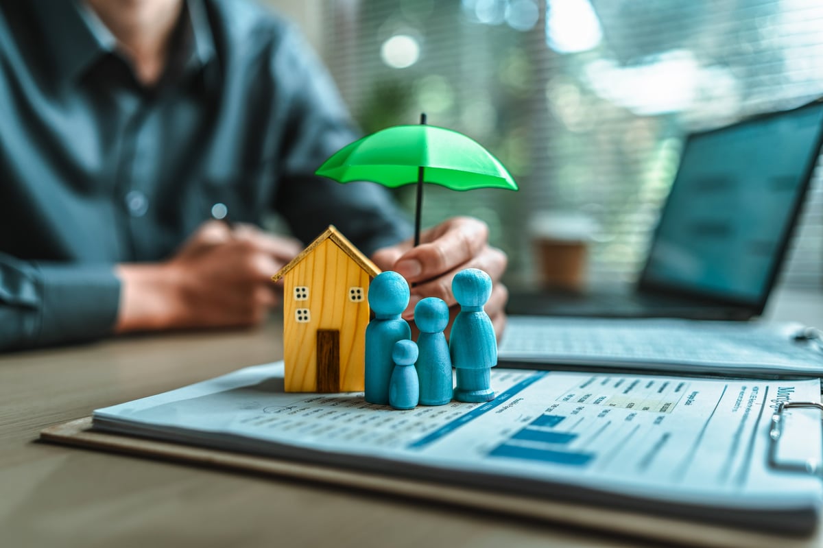 Insurance protection concept with family home and umbrella