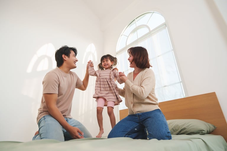 Asian parents playing with their daughter at home showing love and joy